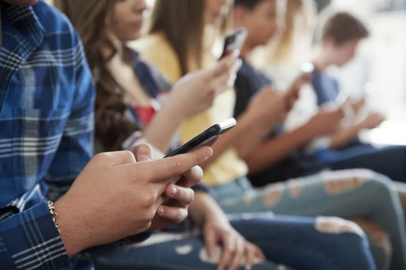 people sat next to each other, on their phones people sat next to each other, on their phones