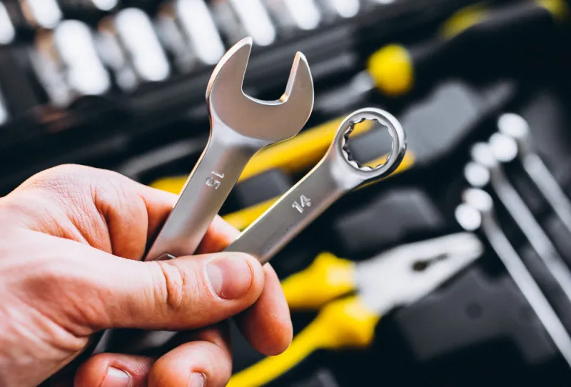 a-hand-holding-a-spanner-over a black-toolbox a-hand-holding-a-spanner-over a black-toolbox