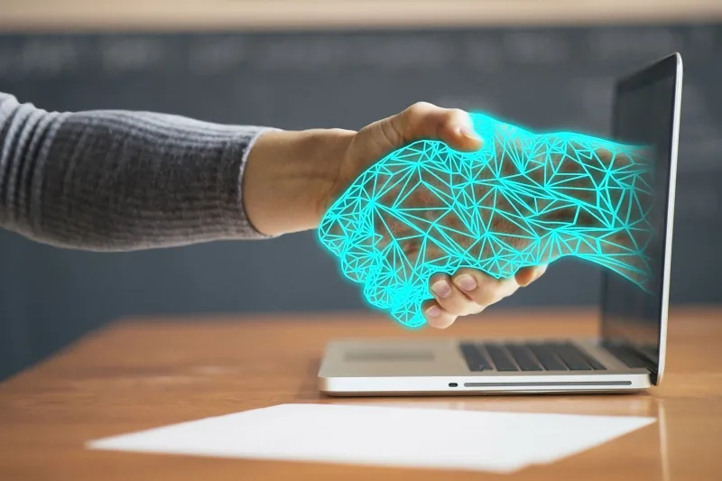 virtual internet hand coming out of laptop holding laptop users hand 