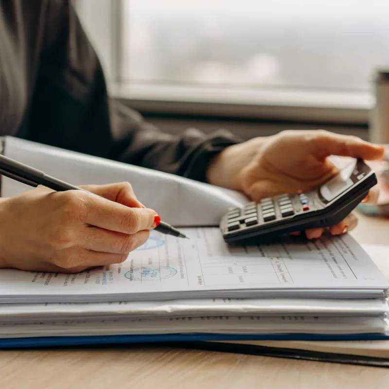 Woman with lots of documents on desk and a calculator Woman with lots of documents on desk and a calculator