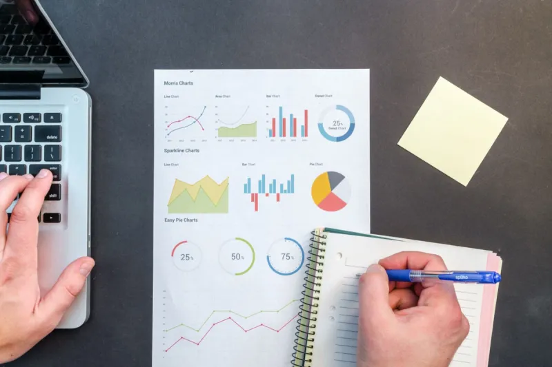 picture of data being collected with one hand on laptop keyboard and other holding blue pen writing information picture of data being collected with one hand on laptop keyboard and other holding blue pen writing information