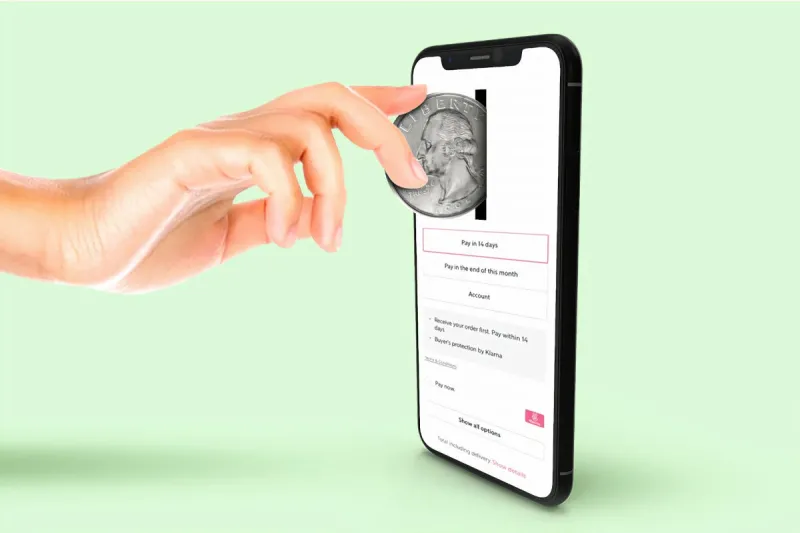 hand on a light blue background putting a coin into a slot on an iphone with a white screen