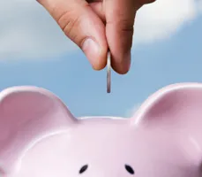 a hand putting money into a piggybank a hand putting money into a piggybank