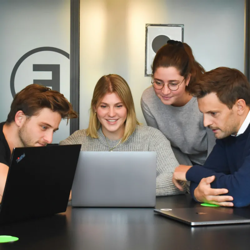 4 professionals viewing a laptop around a desk, showing the small to medium businesses this service can benefit 4 professionals viewing a laptop around a desk, showing the small to medium businesses this service can benefit