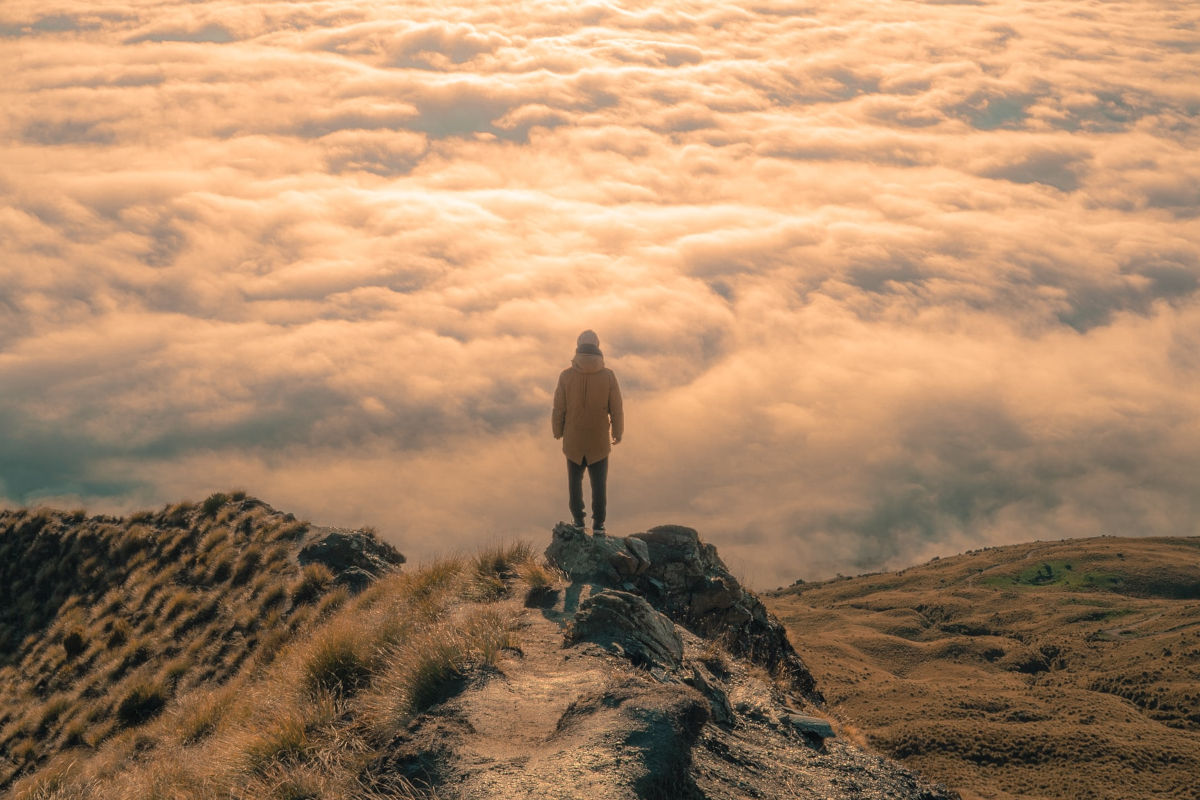 explorer on a mountain with clouds 