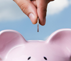 a hand putting money into a piggybank